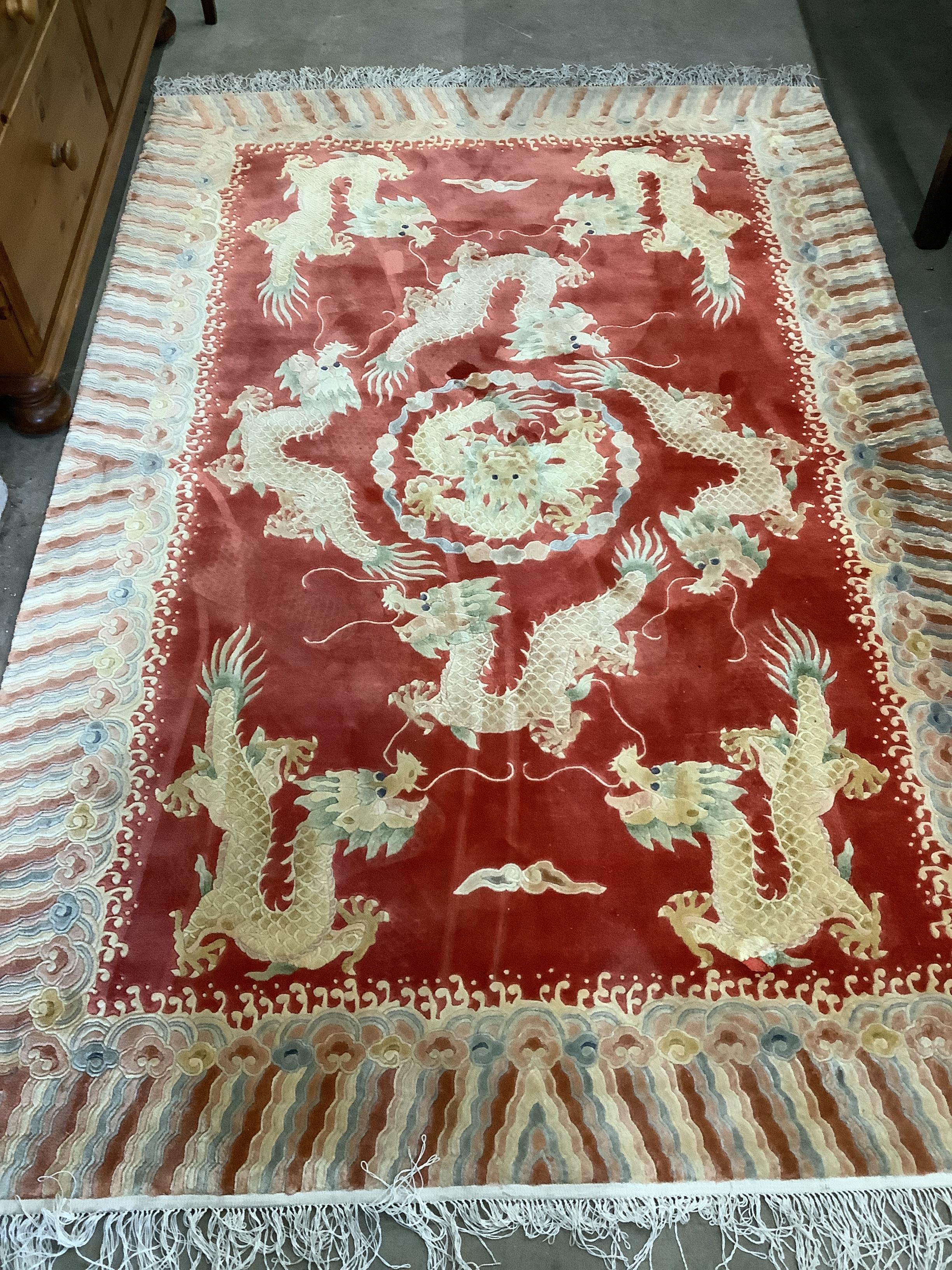 A 20th century Chinese silk 'dragon' rug, the red field woven with dragons within a cloud border, 182 x 122cm